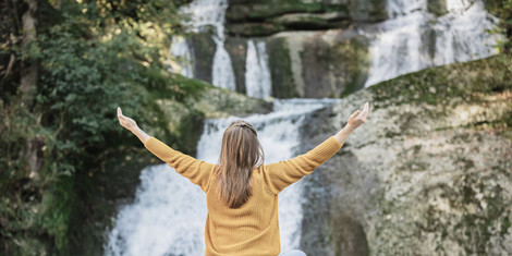 cropped-1750503809-web_version-frau_sitzt_vor_wasserfall_mit_ausgebreiteten_armen_querformat_allgaeu_gmbh__angel_galan_medina